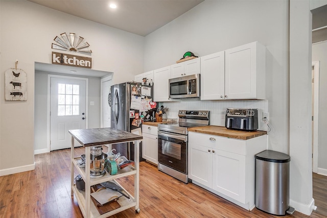 kitchen with wooden counters, decorative backsplash, appliances with stainless steel finishes, light wood-style floors, and white cabinetry