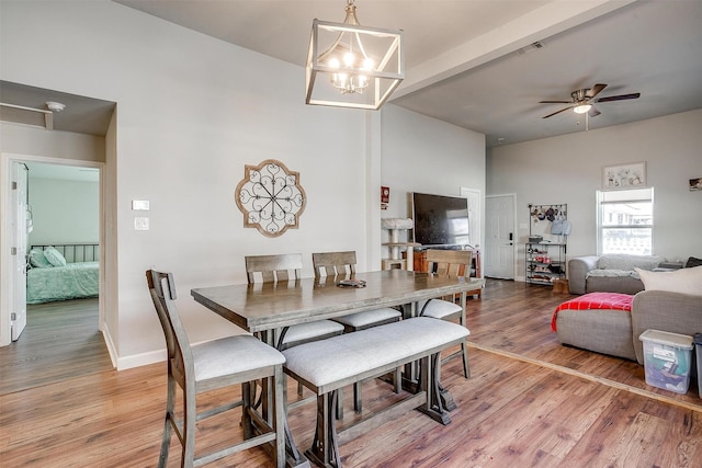 dining room with baseboards, visible vents, beamed ceiling, light wood-style floors, and ceiling fan with notable chandelier