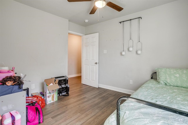 bedroom featuring wood finished floors, a ceiling fan, and baseboards