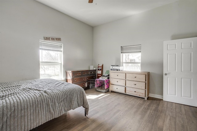 bedroom with lofted ceiling, ceiling fan, multiple windows, and wood finished floors