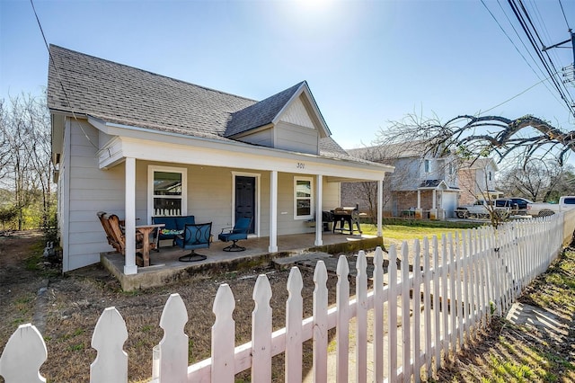 bungalow-style house featuring a porch, a shingled roof, and a fenced front yard