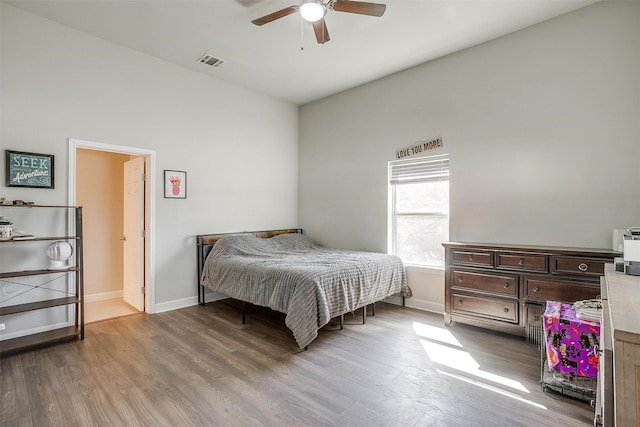 bedroom with ceiling fan, wood finished floors, visible vents, and baseboards