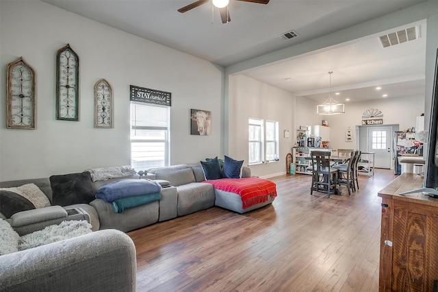 living area with light wood-type flooring, visible vents, and a wealth of natural light