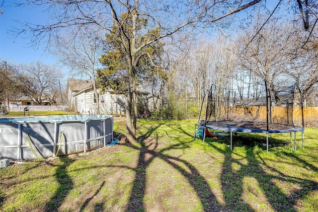 view of yard featuring a trampoline, fence, and a fenced in pool