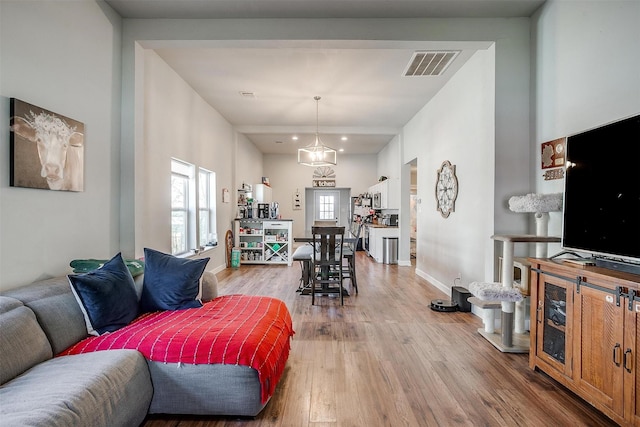 living room featuring light wood finished floors, baseboards, and visible vents