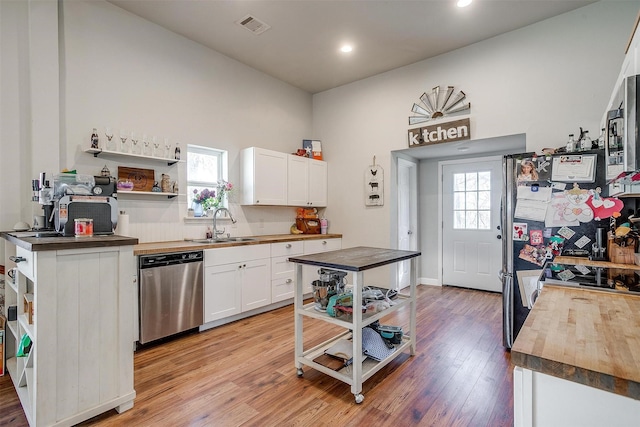 kitchen with light wood-style flooring, butcher block countertops, appliances with stainless steel finishes, open shelves, and a sink