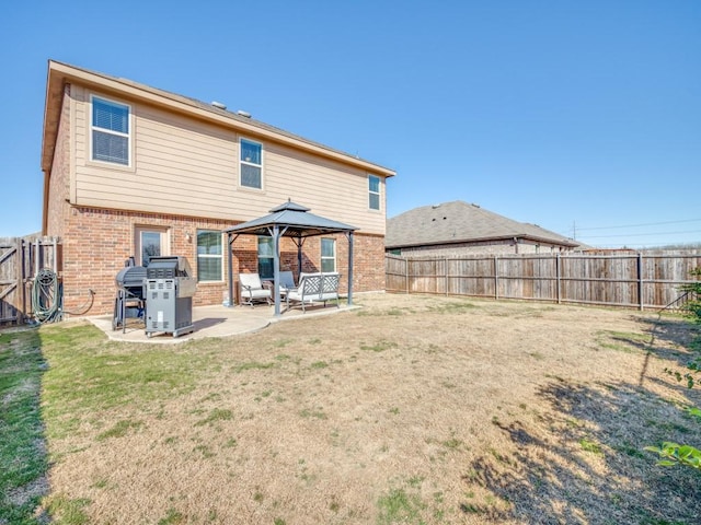 back of property featuring a gazebo, brick siding, a patio, and a fenced backyard