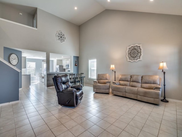 living area featuring high vaulted ceiling, baseboards, and light tile patterned floors