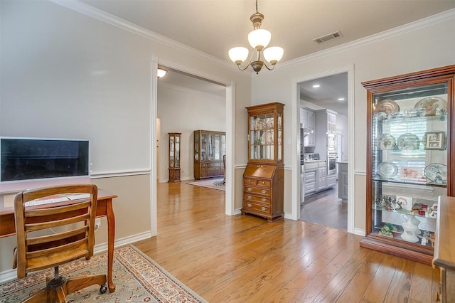 home office with baseboards, visible vents, hardwood / wood-style flooring, ornamental molding, and a chandelier