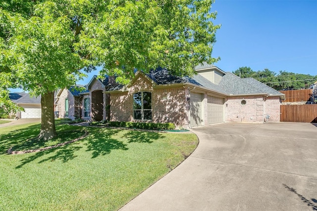 view of front of property featuring an attached garage, brick siding, fence, driveway, and a front lawn