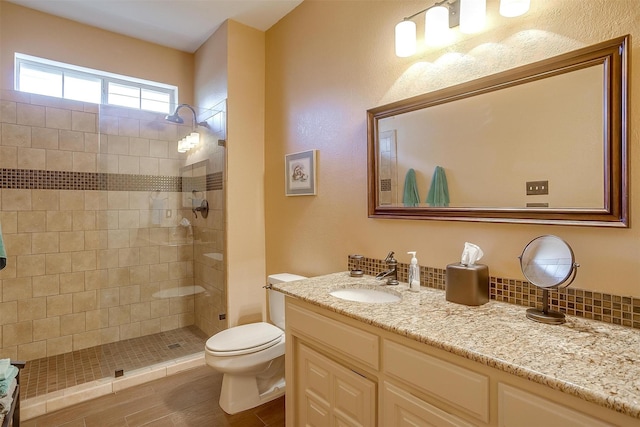 bathroom with a tile shower, vanity, and toilet