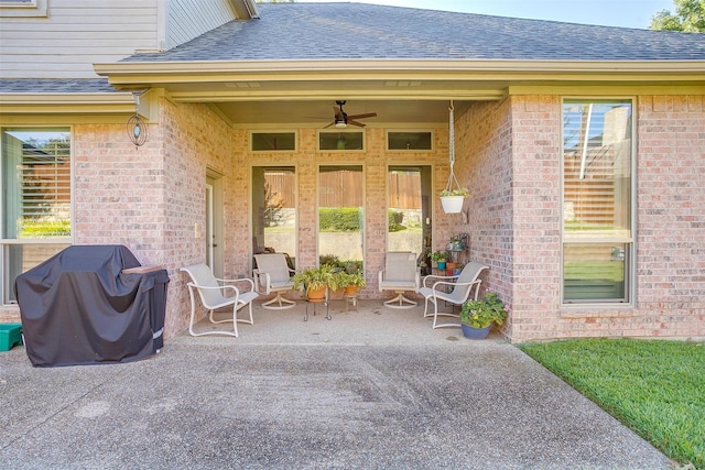 doorway to property with a patio area, a shingled roof, ceiling fan, and brick siding