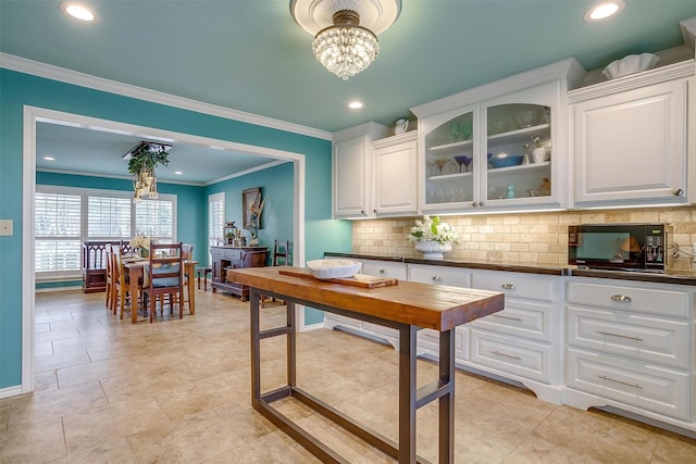 kitchen featuring black microwave, dark countertops, backsplash, and white cabinets