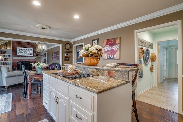 kitchen with a brick fireplace, dark wood-style floors, a kitchen island, and black electric stovetop