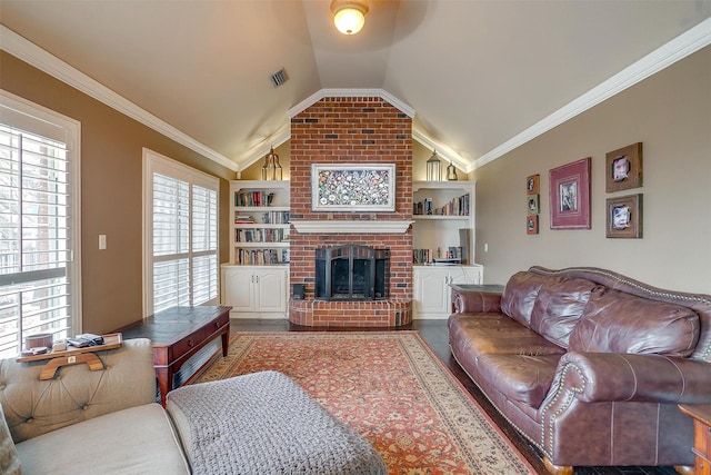 living area featuring built in features, crown molding, a fireplace, visible vents, and vaulted ceiling