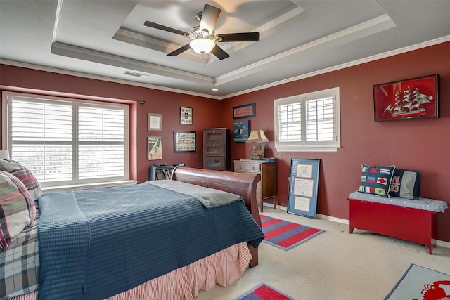 bedroom with carpet floors, visible vents, a ceiling fan, ornamental molding, and a tray ceiling