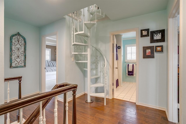 hallway featuring an upstairs landing, hardwood / wood-style flooring, and baseboards