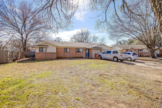 view of front of property featuring brick siding, fence, a garage, driveway, and a front lawn