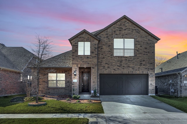 traditional-style home featuring driveway, a lawn, roof with shingles, an attached garage, and brick siding