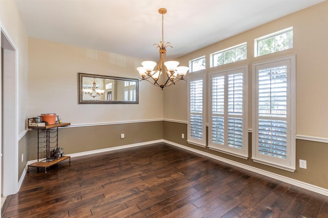 empty room with baseboards, hardwood / wood-style flooring, and an inviting chandelier