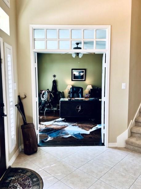 entrance foyer featuring baseboards, stairs, a high ceiling, and tile patterned floors