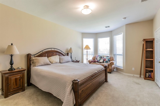 bedroom with baseboards, visible vents, and light colored carpet