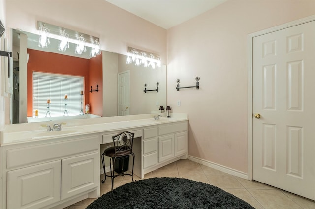 bathroom with double vanity, tile patterned flooring, a sink, and baseboards