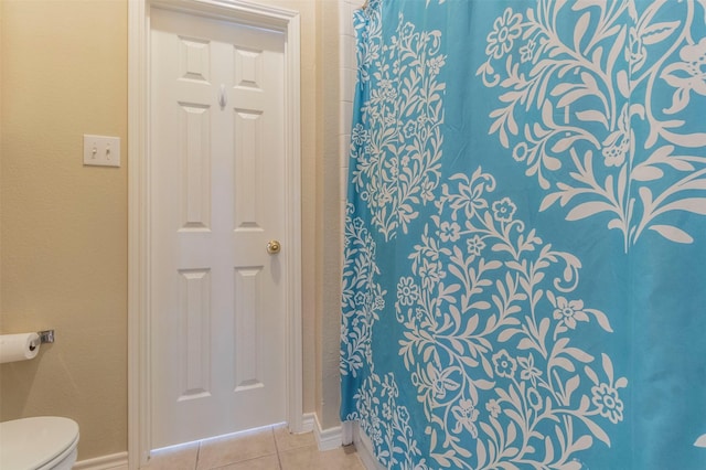 bathroom featuring curtained shower, baseboards, toilet, and tile patterned floors