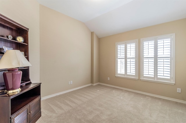 unfurnished room with light carpet, vaulted ceiling, and baseboards