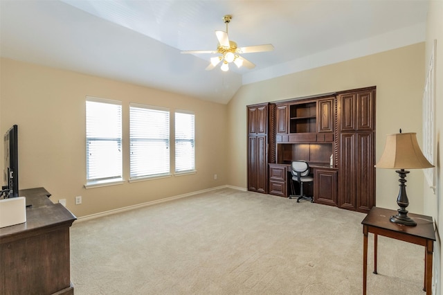 office area featuring ceiling fan, vaulted ceiling, built in study area, and light colored carpet