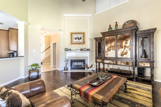 living room with a towering ceiling, wood finished floors, and a tile fireplace