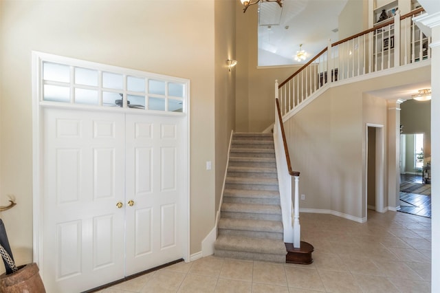 staircase with tile patterned flooring, baseboards, decorative columns, and a high ceiling