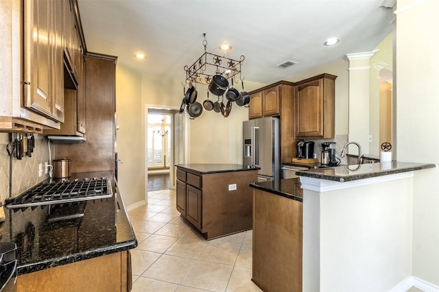 kitchen featuring a center island, light tile patterned floors, visible vents, decorative backsplash, and appliances with stainless steel finishes