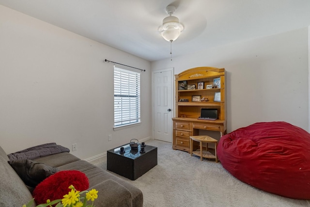 living room featuring a ceiling fan, light colored carpet, and baseboards