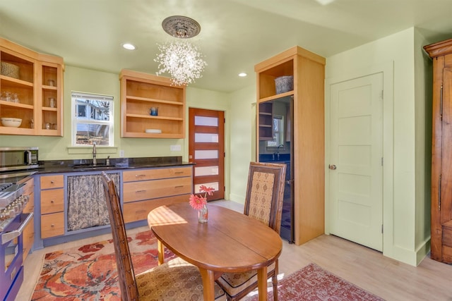 kitchen with dark countertops, open shelves, a sink, stainless steel microwave, and a notable chandelier