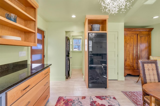 interior space with open shelves, dark stone countertops, and light wood-style floors