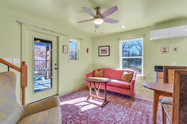 sitting room featuring baseboards, wood finished floors, a ceiling fan, and a wall unit AC