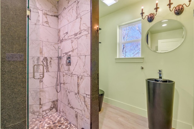 bathroom featuring wood finished floors, toilet, baseboards, and a stall shower