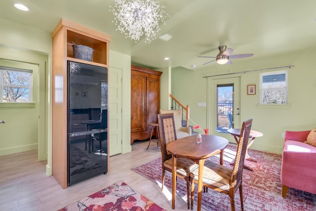 dining space featuring stairs, light wood-style flooring, ceiling fan with notable chandelier, and recessed lighting