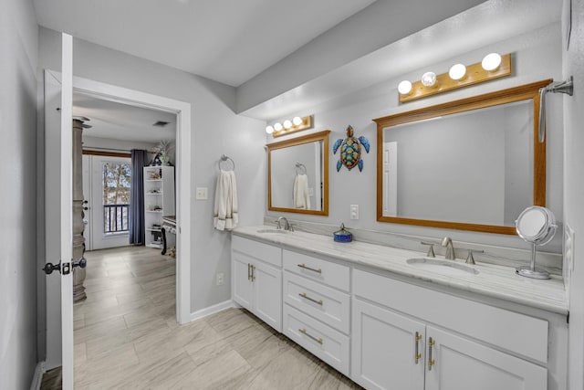 bathroom featuring a sink, baseboards, and double vanity