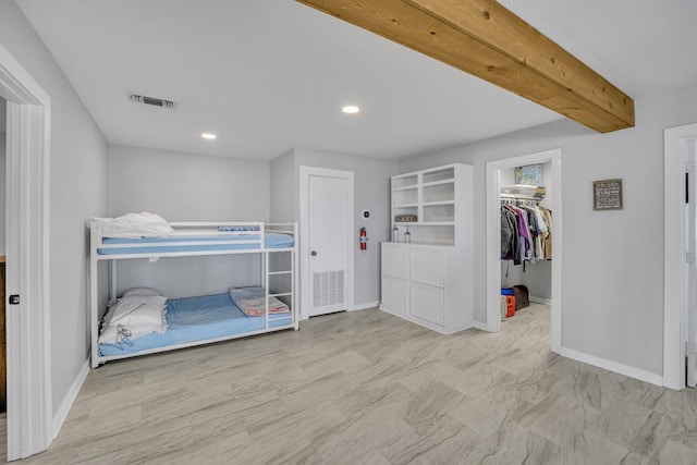 bedroom featuring a walk in closet, visible vents, and baseboards