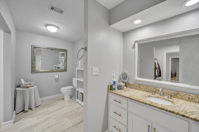 bathroom featuring a textured ceiling, toilet, vanity, visible vents, and baseboards