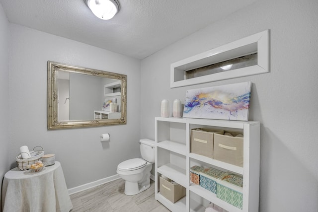 bathroom featuring toilet, baseboards, and a textured ceiling