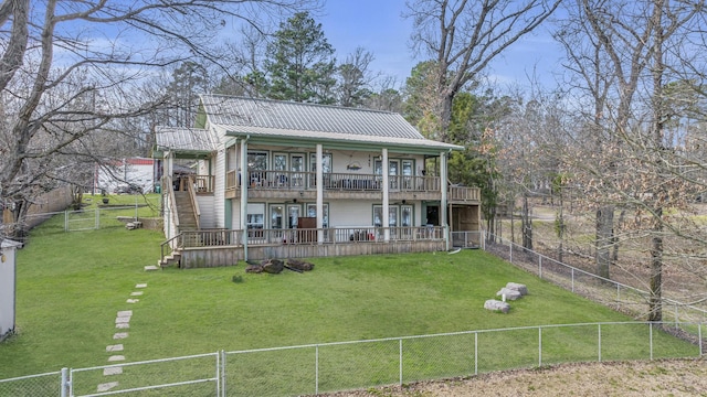 rear view of house featuring a lawn, a fenced backyard, stairway, metal roof, and a wooden deck