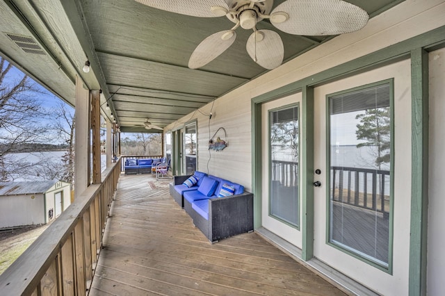 wooden deck featuring visible vents, ceiling fan, and an outdoor structure