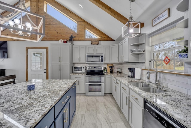 kitchen with blue cabinetry, lofted ceiling, backsplash, appliances with stainless steel finishes, and a sink