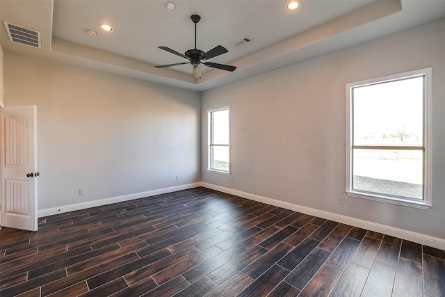 spare room with baseboards, wood tiled floor, visible vents, and a tray ceiling