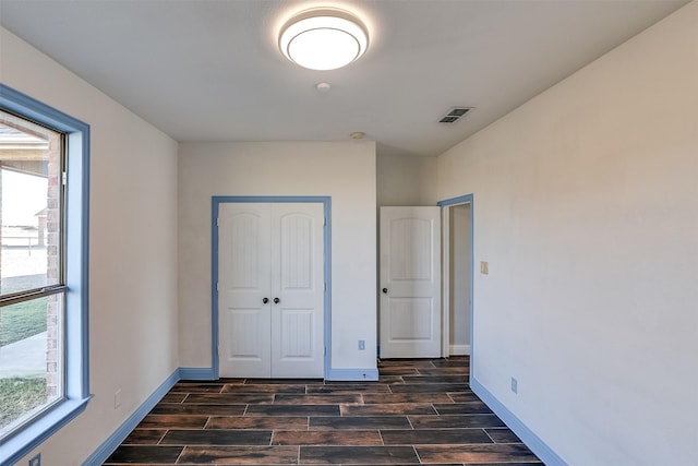 unfurnished bedroom with wood finish floors, multiple windows, and visible vents