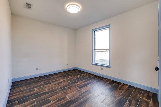 empty room with baseboards, visible vents, and wood finish floors