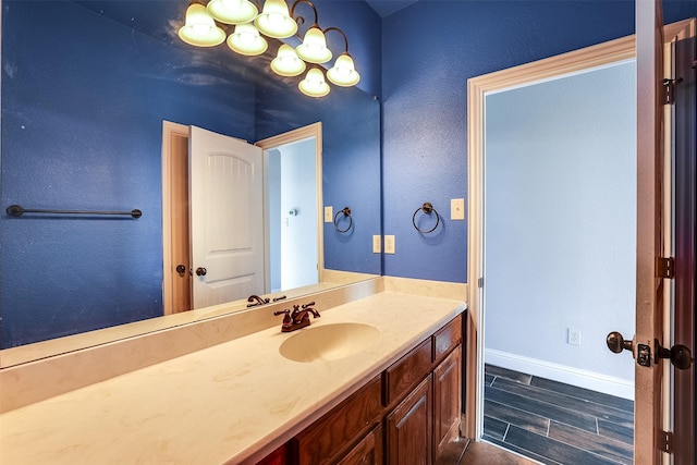 bathroom featuring a notable chandelier, wood finished floors, vanity, and baseboards